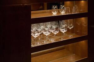 Clean wine glasses are in the wine cabinet in restaurant, local illumination photo