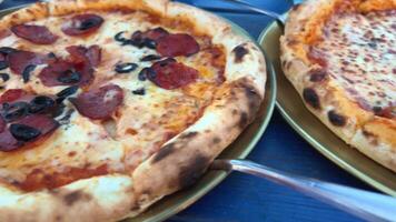 two pizzas pizza with cheese and Margherita and pizza with salami on a blue table video