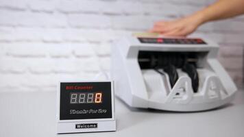 elektronisch Geräte im Bank. Bank Operationen auf ein Zähler Maschine. automatisch Mechanismus zum Bank finanziell Operationen. Frau setzt ein bündeln von Dollar im ein Geldzählen Maschine mit seine Hand. video