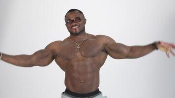 Athletic black man posing on camera. Portrait of a smiling african american guy without shirt showing his muscles and looking on camera on white background. video
