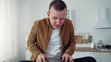 Nervous businessman during quarantine. Young man freelancer with a laptop sitting on a table in the kitchen and typing angrily. Work at home during lockdown. video