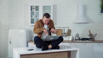 Young man pressing buttons on a laptop at home. Funny face of a businessman after working long hours on a computer. Tired mad man on the table at home with a laptop. video