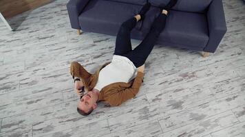 Young man speaking the phone at home. Tired man working through the phone while lying on a floor. Top view. video