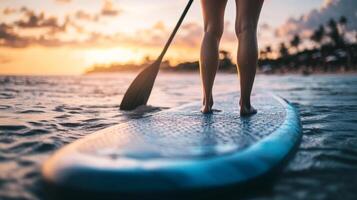 Experience summer adventure with stand up paddle boarding on a sandy beach during sunset at a tropical paradise photo