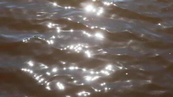 Slow motion of sunlight dancing across dark water surface, creating mesmerizing ripples and sparkling reflections with gentle, fluid movement. video