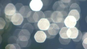 Sunlight glistening across rippling water surface, creating mesmerizing bokeh effect with soft, defocused light patterns reflecting blue and white hues. video