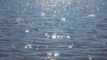 Soft sunlight dancing across rippling water surface, generating mesmerizing glittering patterns of luminous blue hues. video