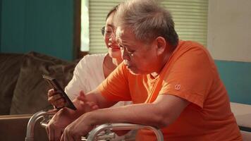Elderly man receiving guidance from a caregiver while learning how to use a smartphone for communication daily life. video