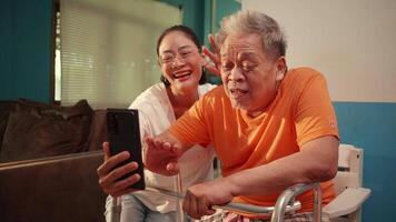 Elderly man receiving guidance from a caregiver while learning how to use a smartphone video