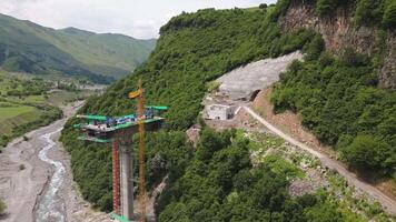 Kazbegi, Georgia , 2024 - aerial view cranes and bridge foundation pillars on construction site of new highway road project built by chinese builders.Avalanche bypass tunnel.Tbillisi - Lars video