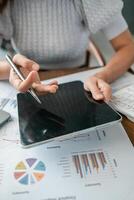 Close-up of hands using a tablet to review financial charts and graphs, showcasing business analysis and technology. photo