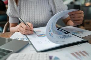 Close-up of a woman reviewing financial documents with charts and graphs, highlighting business analysis and strategic planning. photo
