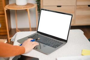 A person interacts with a laptop featuring a blank screen, set on a cozy table, ideal for remote work or online learning in a home environment. photo