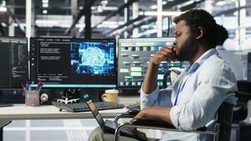 Data center computer scientist in wheelchair using AI node tree software to minimize system downtime. Server hub employee in disability using artificial intelligence visual programming tool, camera B video