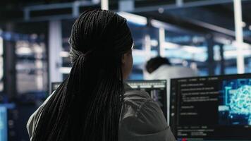 Data center programmer using artificial intelligence deep learning models to configure infrastructure. IT staff member works on AI programming language in server room, optimizing system, camera B video