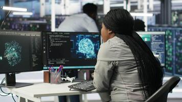 Server room specialist applies artificial intelligence technology to minimize system downtime. African American worker develops and deploys AI solutions to optimize data center equipment, camera B video