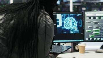 Data center engineer in wheelchair and colleague oversee automated tasks using node tree programming tool. Inclusive server farm team adjusts system settings based on AI analytics, camera B video
