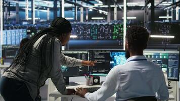 Manager supervising data center engineer using AI neural network models to configure hardware. Team leader overseeing employee using machine learning programming language to optimize systems, camera A video