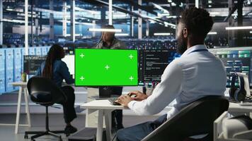 Data center IT expert uses isolated screen PC to apply deep learning node tree tech analyzing datasets. Server hub engineer uses visual programming on chroma key PC to identify data patterns, camera A video