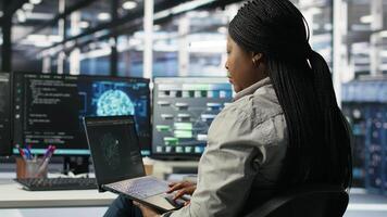 Server room IT expert using laptop to apply artificial intelligence technology minimizing system downtime. Technician using notebook to develop and deploy AI solutions optimizing equipment, camera B video