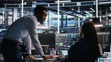 Data center manager supervising engineer using node tree tool to identify equipment performance issues. Server hub team leader talks with IT specialist reviewing data analysis graph, camera A video
