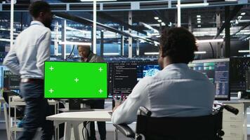 Data center worker with paraplegia using green screen PC to apply node tree programming. Server hub admin with disability uses visual programming on mockup computer to identify data patterns, camera A video