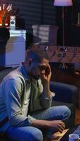 Vertical African american person receiving some bad news while doing remote work tasks, feeling overworked and under pressure to complete all his assignments. Young adult deals with burnout. Camera A. video
