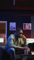 Vertical Tired black man failing some tasks and struggling to focus at home, dealing with burnout after doing overtime. Overworked fatigued person closes the laptop and taking a break. Camera A. video