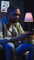 Vertical Chill self employed guy enjoying a break with his mobile phone on sofa, texting friends on social media and laughing. Cozy living room showcases work and leisure in remote lifestyle. Camera A. video