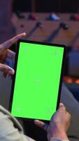 Vertical Relaxed male tech user holding device with isolated mockup screen in his living room, sitting on the couch and teleworking. African american happy guy browses the internet, outsourcing. Camera B. video