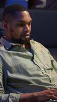 Vertical Guy checking financial balance and working on accounting analysis, ensuring company revenue growth at home. African american worker enjoys remote job using economy statistics. Camera B. video