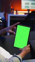 Vertical Relaxed male tech user holding device with isolated mockup screen in his living room, sitting on the couch and teleworking. African american happy guy browses the internet, outsourcing. Camera A. video