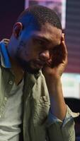Vertical African american person receiving some bad news while doing remote work tasks, feeling overworked and under pressure to complete all his assignments. Young adult deals with burnout. Camera B. video