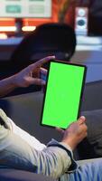 Vertical Black remote worker looking at green screen on his device at home, relaxing in the living room and solving freelancing tasks. Guy being casual in trendy apartment, teleworking. Camera B. video
