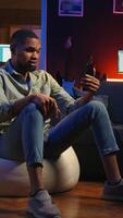 Vertical African american guy attends web conference call on laptop sitting at home, joining an remote webinar to discuss about solving daily tasks. Teleconference in the living room. Camera A. video