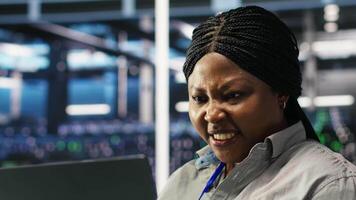 Annoyed data center admin having trouble doing node tree programming. Irked woman in server room having glitching issues while using predictive AI visualization systems on notebook, camera B closeup video
