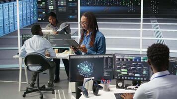 Woman in server hub using AI visualization insights on tablet device to optimize system health. Data center computer scientist analyzing infrastructure issues using node tree tools, camera A video