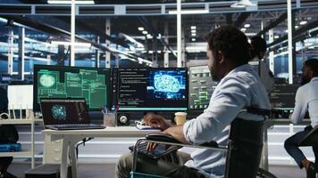Man with paraplegia in server hub trying to protect hardware from hacker attack stealing sensitive information. Data center specialist in wheelchair fighting virus during security breach, camera A video