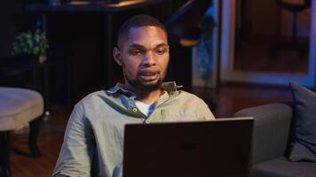 Black male freelancer taking online course to learn new skills from home, attend online call and watching lecture from loft. Young man participates at a virtual training class. Camera B. video