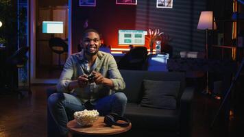 Cheerful confident person winning the games championship, celebrating and feeling pleased with his success. Happy joyous black guy enjoying free time and a gaming win. Camera A. video