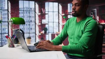 Black freelancer thinking about new solutions to increase profit and reach, multitasking to find ideas for financial growth. Young remote worker uses his creativity for success. Camera B. video