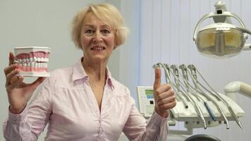 Senior woman proudly displays a model of human teeth video