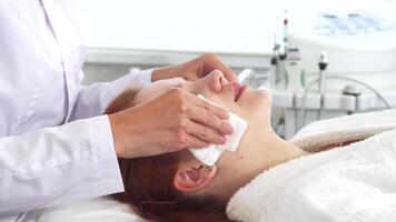 Cosmetologist gently wipes client's face with soft napkins video