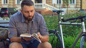 Cyclist engrossed in a book while relaxing on a bench video