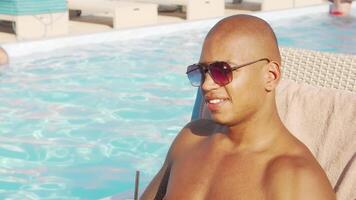 Charming African man enjoying a refreshing cocktail by the shimmering pool video