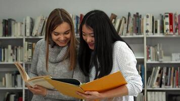 Two female students enthusiastically compare notes in a library video