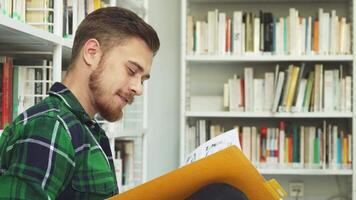 Joyful young man reading in a library video