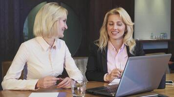 Two friendly blondes engage in a lively discussion about work video