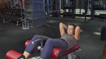 Focused young girl engages in ab exercises on a specialized simulator video