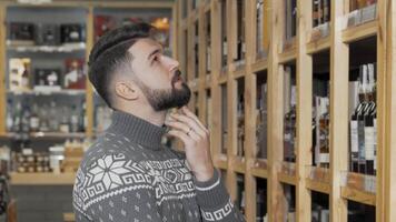 Thoughtful bearded man contemplating wine selections in a cozy store video